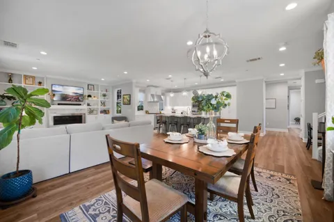 a dining room with wooden floor a chandelier a wooden table and chairs