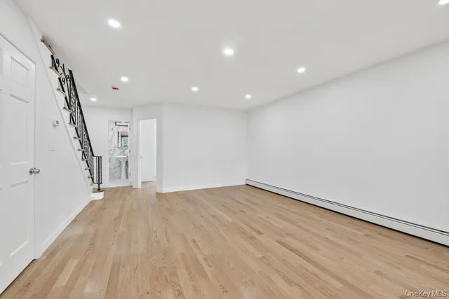 a view of an empty room with wooden floor and stairs