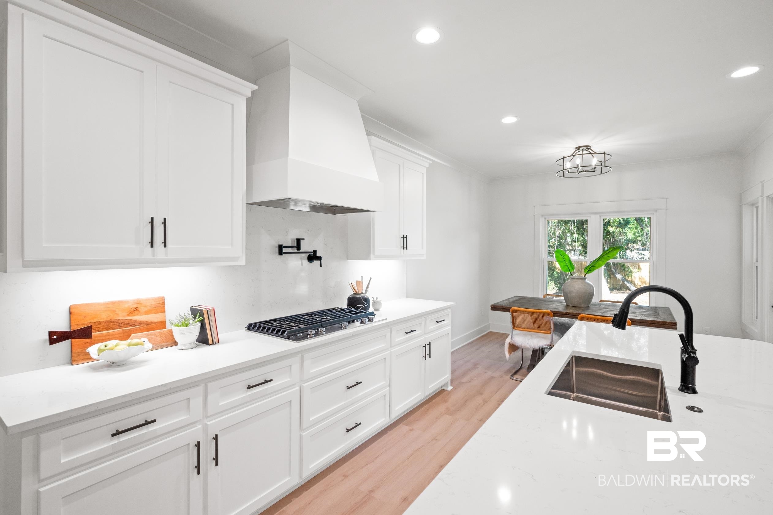 28889 Canal Road Orange Beach, AL 36561 - Photo 15 of 55 Kitchen featuring sink, stainless steel gas cooktop, light hardwood / wood-style flooring, white cabinets, and custom range hood