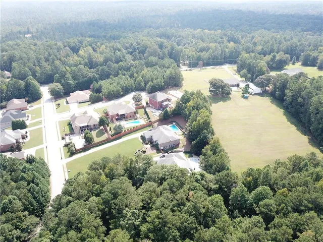 an aerial view of residential house with outdoor space and trees all around
