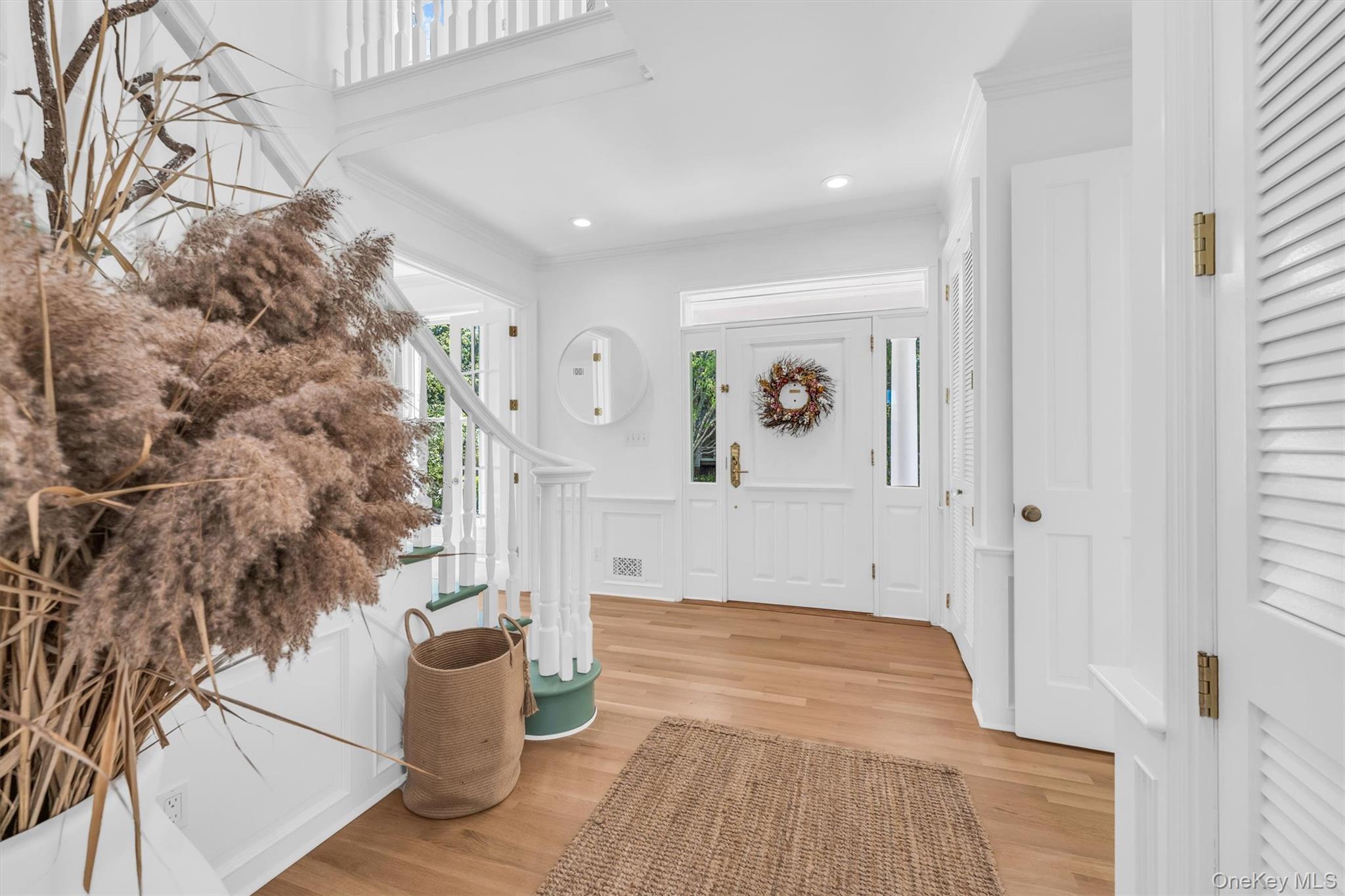 68 South Howells Point Road Bellport, NY 11713 - Photo 7 of 47 Foyer entry featuring wood flooring, a white paneled front door with sidelights, and a staircase with white balusters