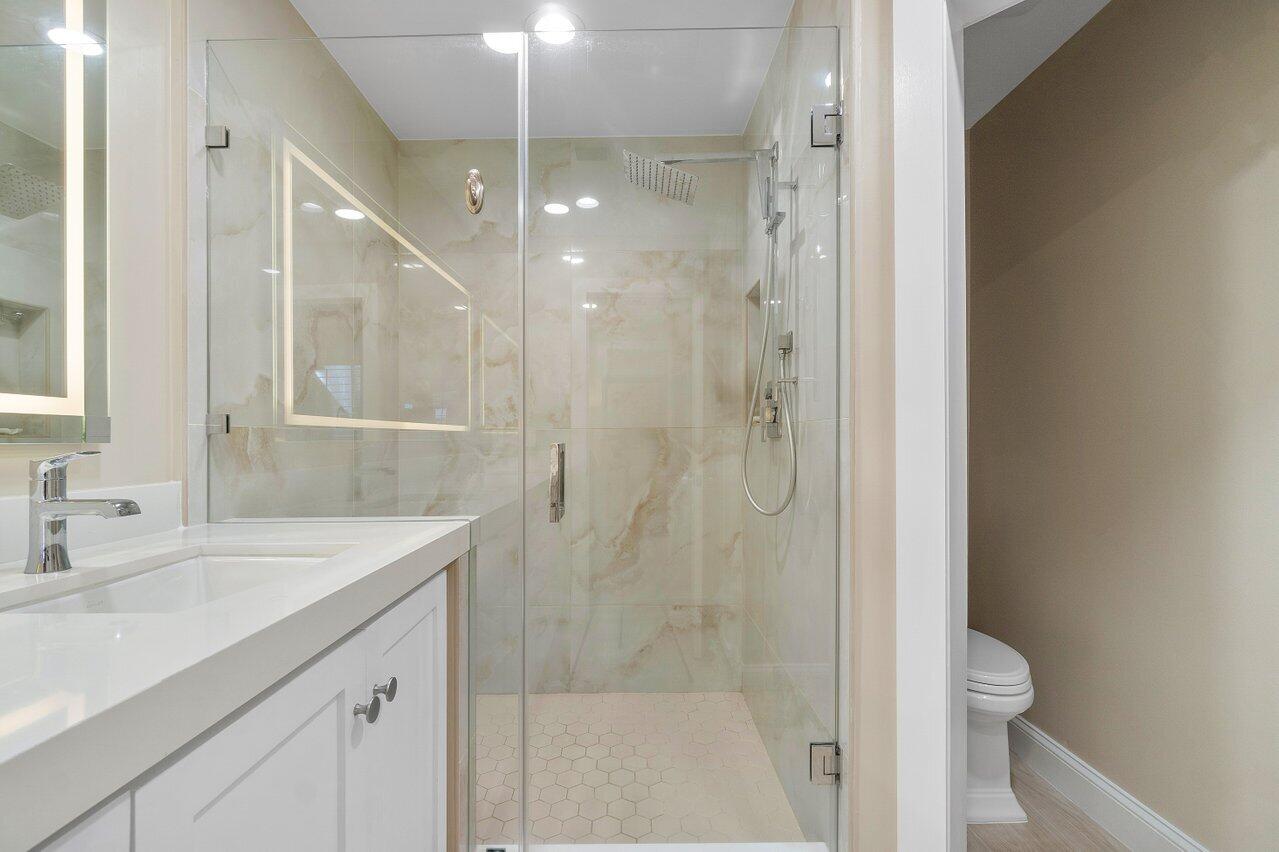 120 Inlet Way, Unit 204 Palm Beach Shores, FL 33404 - Photo 21 of 27 a bathroom with a shower sink vanity and mirror
