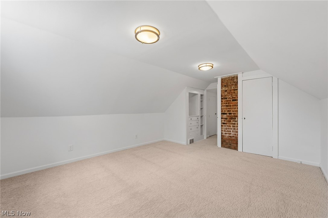 7750 Lewis Road Olmsted Falls, OH 44138 - Photo 33 of 50 Carpeted room featuring a sloped ceiling, built-in shelving with drawers, exposed brick accent, and flush-mount lighting fixtures