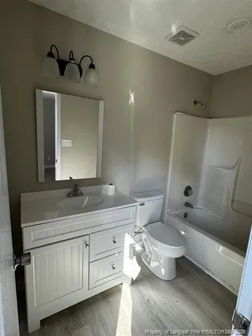 a bathroom with a granite countertop sink toilet and mirror