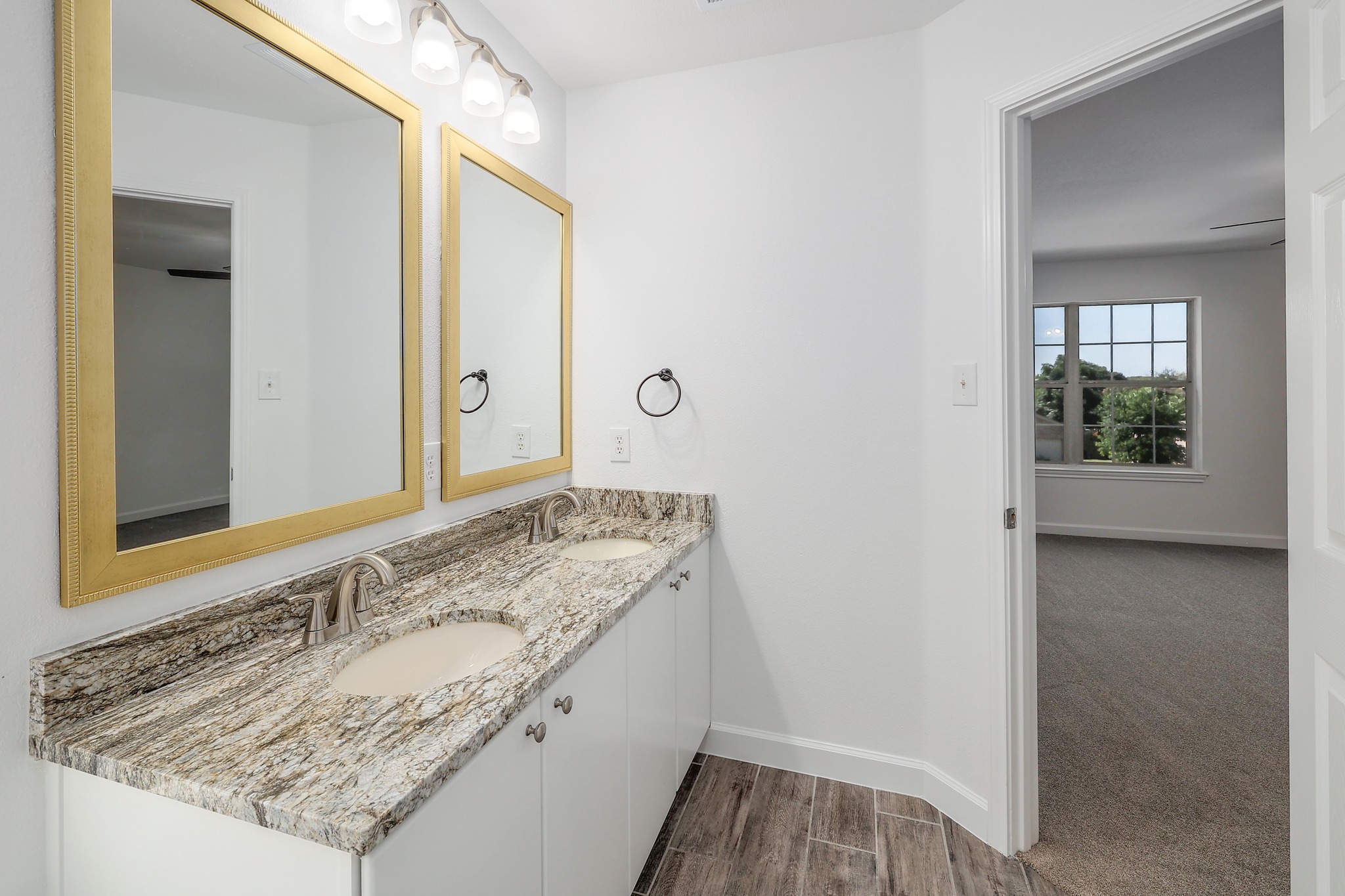 709 Los Robles Road Leander, TX 78641 - Photo 21 of 26 Double vanities with sleek stone counters offer ample space in this well-appointed bathroom.