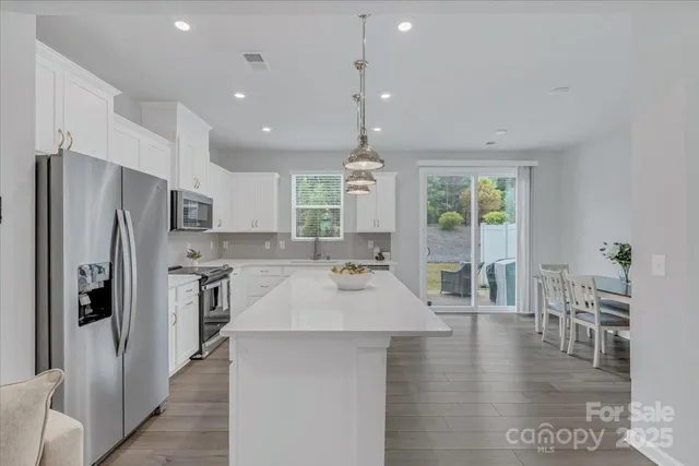 a large kitchen with kitchen island a large window a refrigerator a dining table and chairs