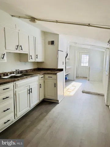 a large kitchen with cabinets and wooden floor