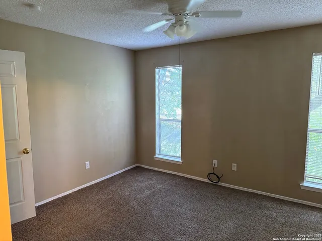 an empty room with windows and fan