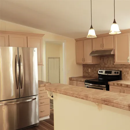 a kitchen with stainless steel appliances granite countertop a refrigerator a sink and a stove