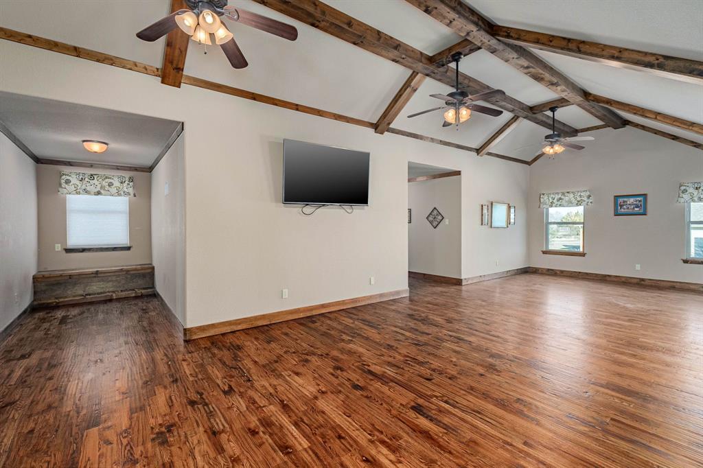 3028 Harrell Road Howe, TX 75459 - Photo 23 of 39 More Game Room view showing the wood beam ceiling, dormer area. The walk-in closet is accessed from the right dormer area and is the length of the wall with TV mounted on it. (TV & mount are excluded from the sale of the home)