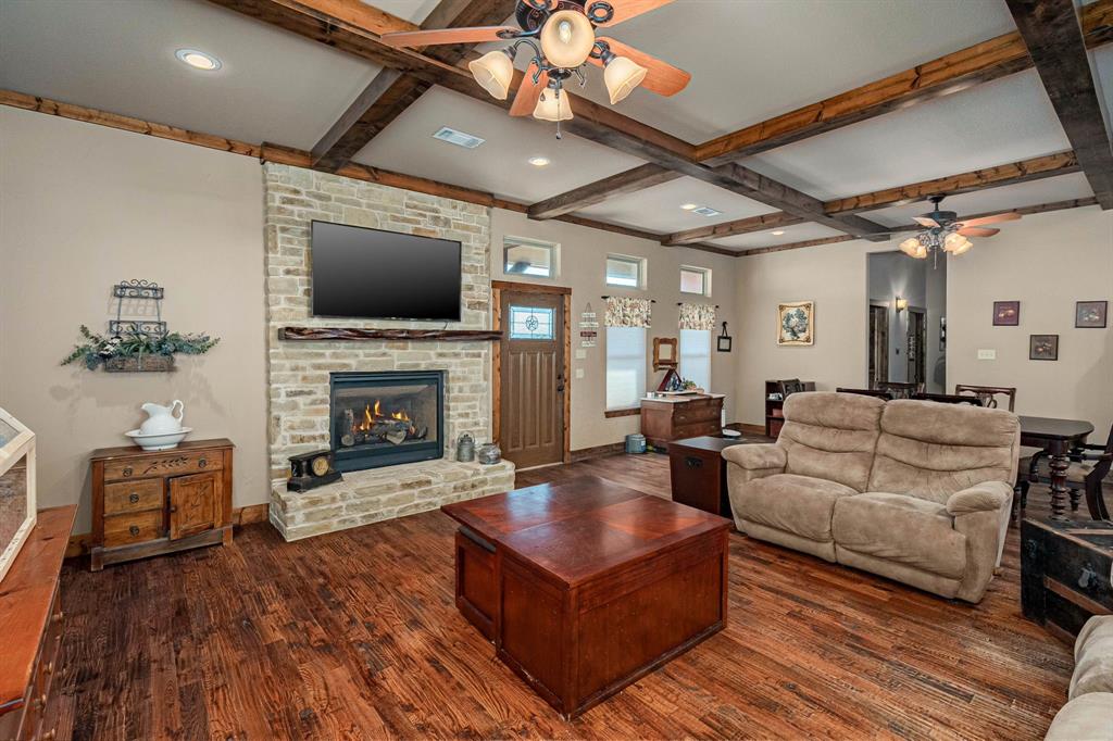 3028 Harrell Road Howe, TX 75459 - Photo 5 of 39 The main living room (den) has a full stone enhanced exterior finished fireplace, remote-controlled propane logs, handsome wood floors and wood beam ceiling.