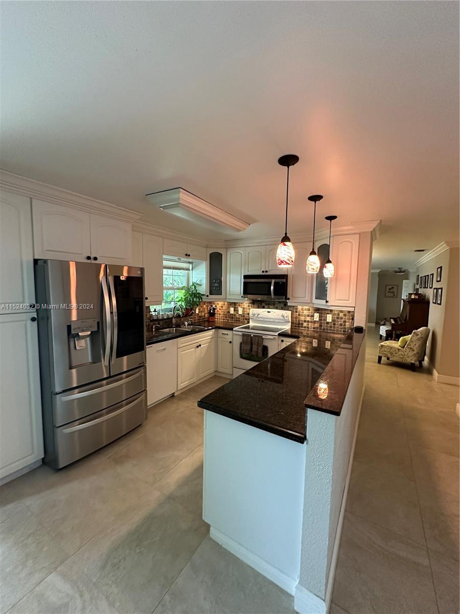 14944 Southwest 144th Court Miami, FL 33186 - Photo 10 of 34 a kitchen with stainless steel appliances kitchen island granite countertop a refrigerator a stove and a sink