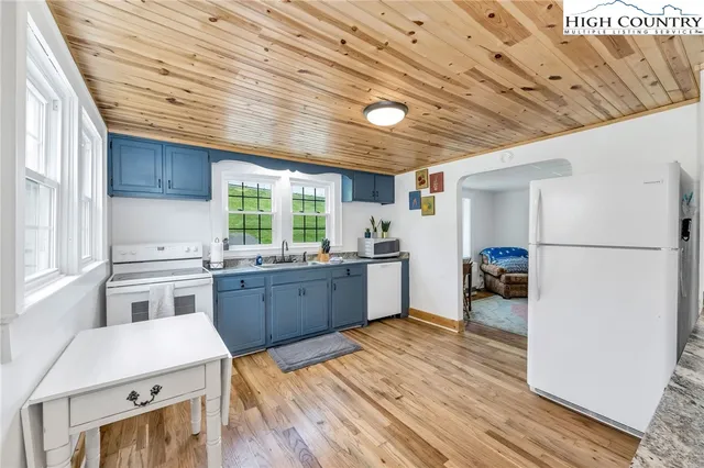 a kitchen with stainless steel appliances granite countertop a refrigerator a sink dishwasher a stove and white countertops with wooden floor