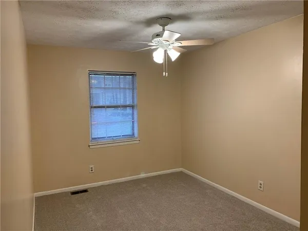 an empty room with a chandelier fan and windows
