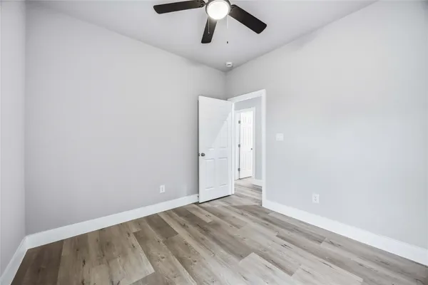 an empty room with a ceiling fan and wooden floor