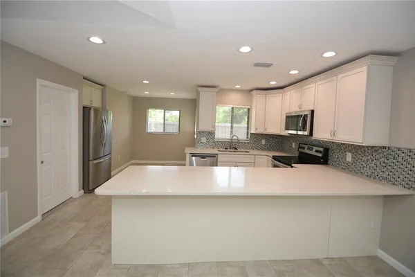 a large kitchen with granite countertop a large counter top stainless steel appliances a sink cabinets and a window