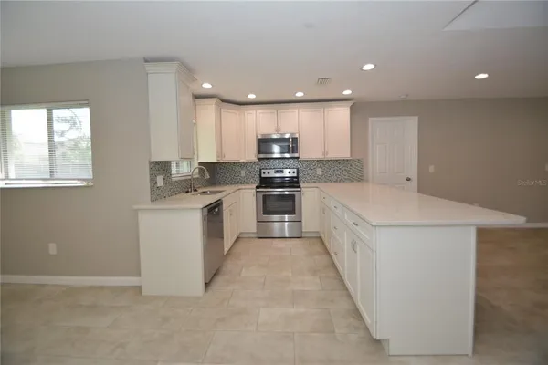 a kitchen with kitchen island sink stove and cabinets