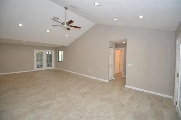 an empty room with windows and ceiling fan