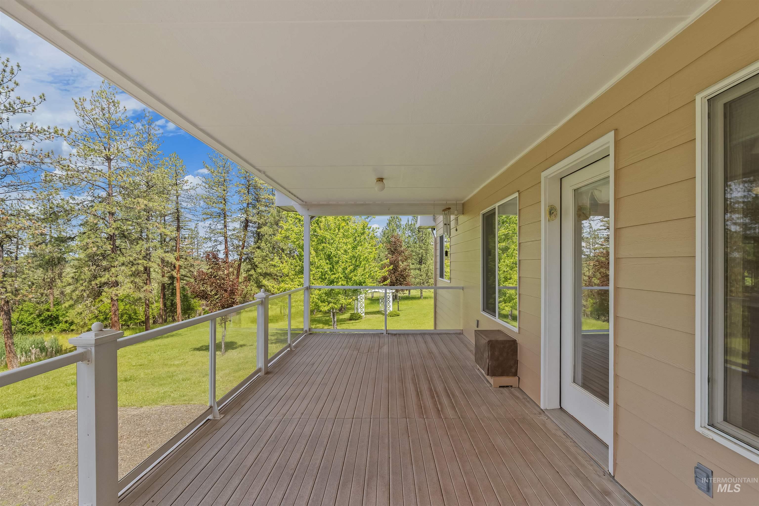 743 Wall Crk Road Stites, ID 83552 - Photo 25 of 48 Expansive covered deck featuring wood-finish flooring, glass panel railings, and access to the interior via a full-lite door and multiple windows