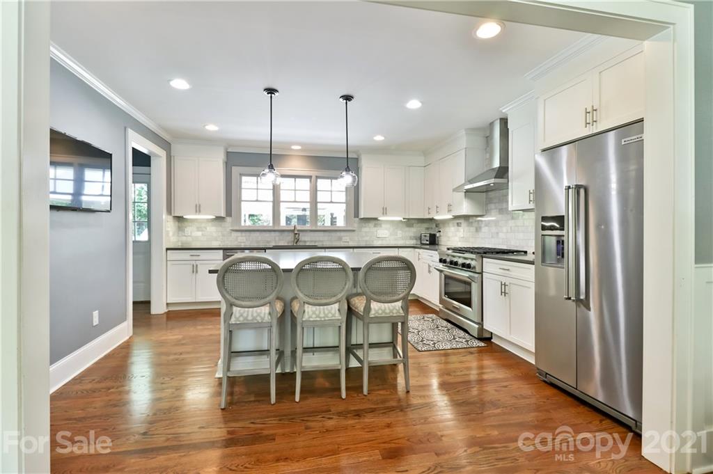 1901 Truman Road Charlotte, NC 28205 - Photo 12 of 39 a kitchen with stainless steel appliances granite countertop a refrigerator a stove top oven a sink dishwasher a dining table and chairs with wooden floor