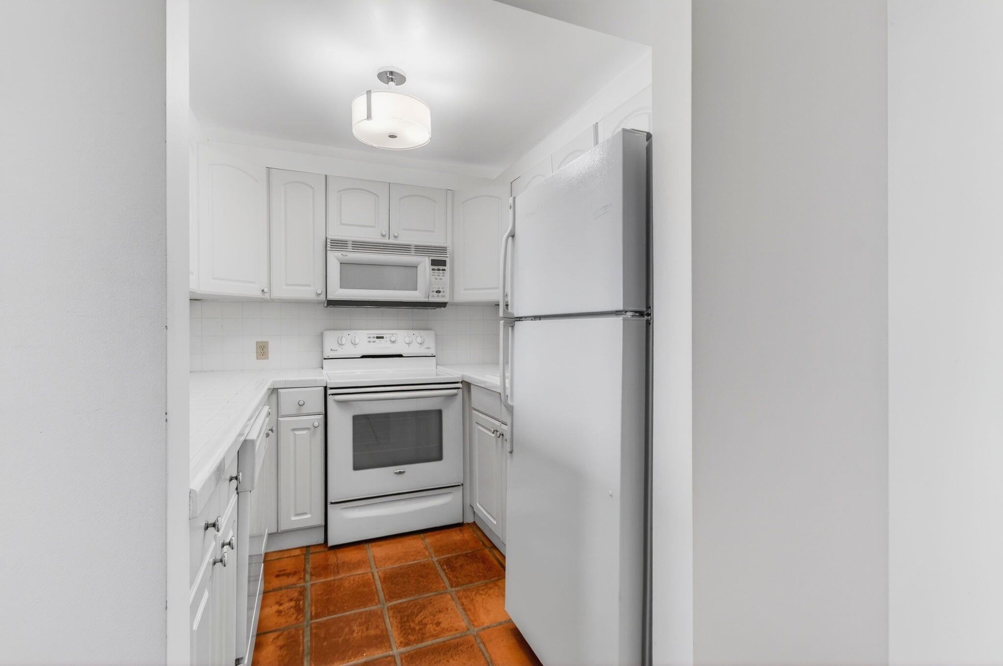 359 Brighton I Boca Raton, FL 33434 - Photo 14 of 34 a kitchen with white cabinets and white appliances