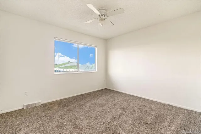 an empty room with windows and ceiling fan