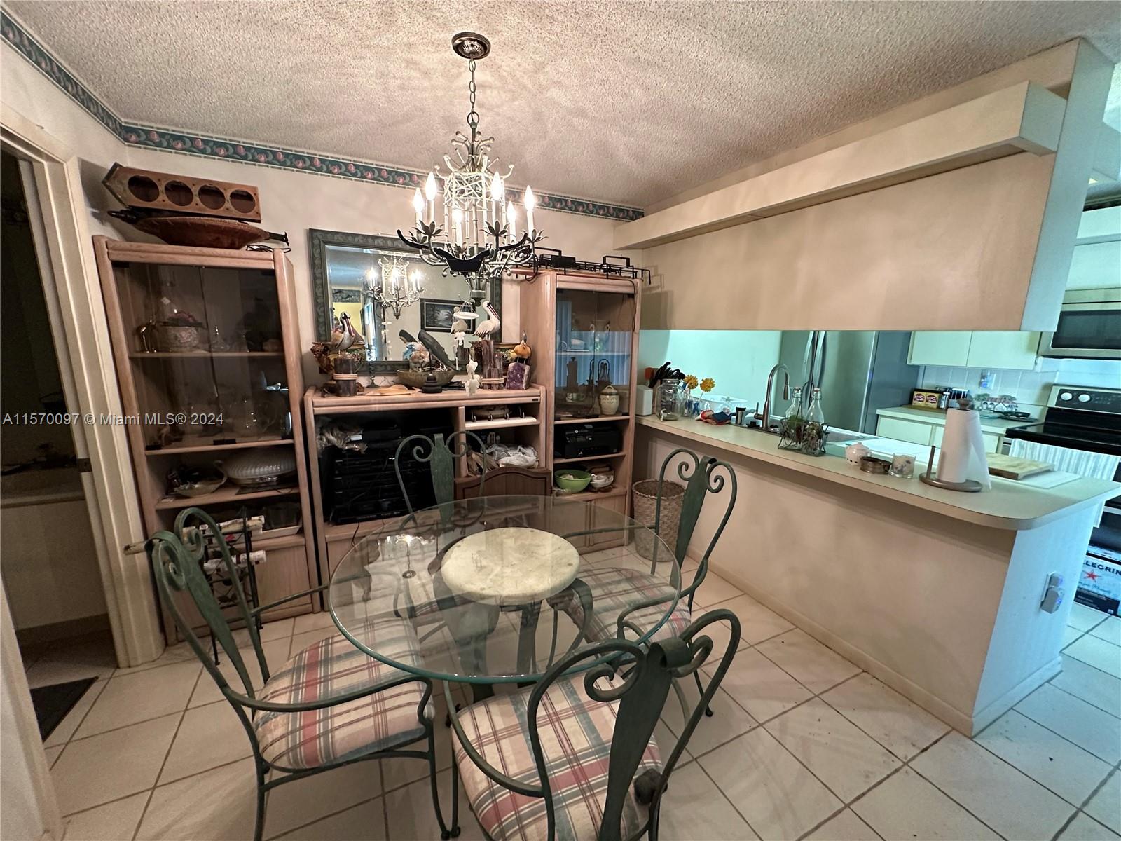 2413 24th Court Jupiter, FL 33477 - Photo 14 of 32 a dining room with furniture a chandelier and kitchen view