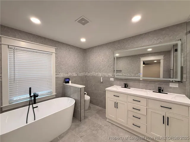 a bathroom with a double vanity sink a mirror and a bathtub