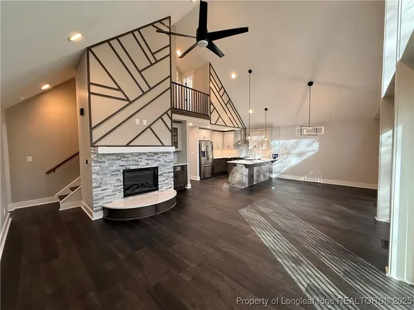 a view of a livingroom with furniture wooden floor staircase and a kitchen view