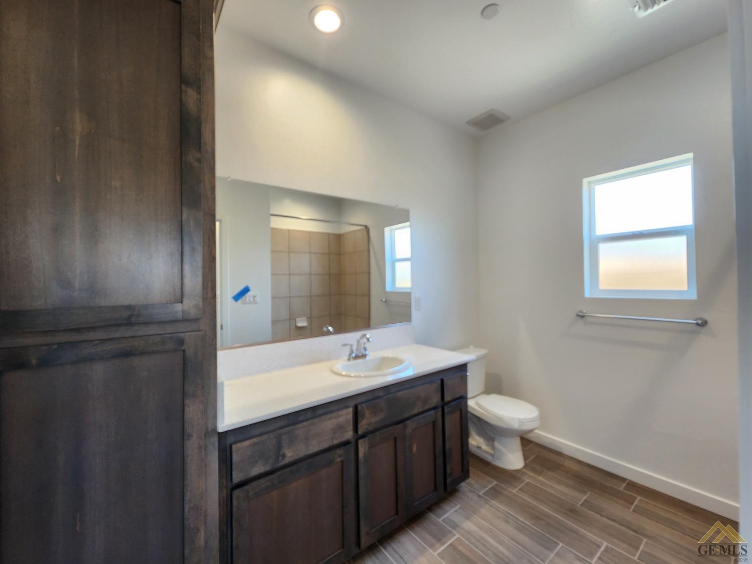 Undisclosed Address Bakersfield, CA 93313 - Photo 15 of 22 a bathroom with a double vanity sink a toilet and a mirror