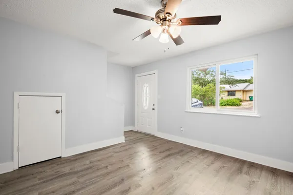 a view of an empty room with wooden floor and a window