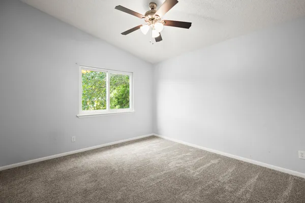 an empty room with a window and a fan