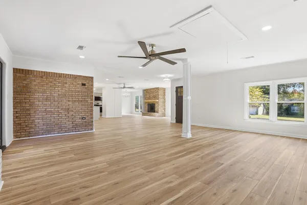 a view of an empty room with wooden floor and a kitchen