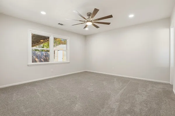 an empty room with windows and fan