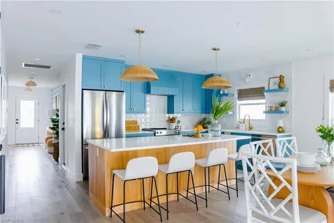 a kitchen with stainless steel appliances a dining table chairs and white cabinets