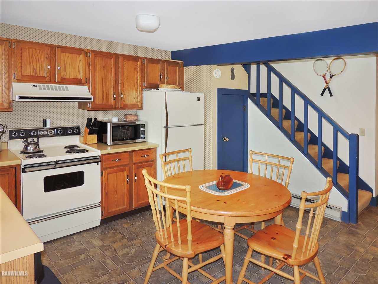 21 Thatcher Lane Galena, IL 61036 - Photo 5 of 25 a white kitchen with a stove a refrigerator a dining table and chairs