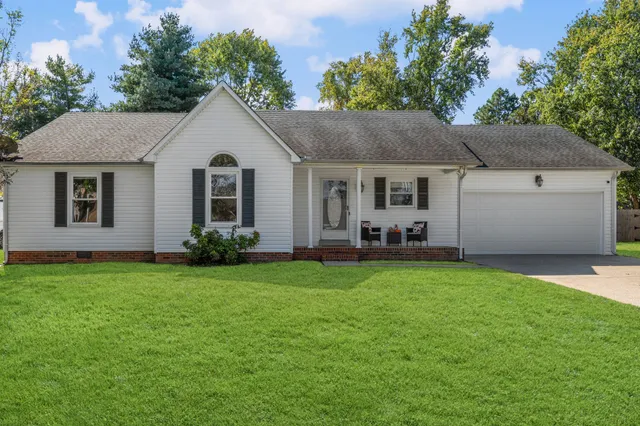 a front view of house with yard and trees in the background
