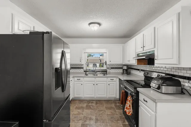 a kitchen with stainless steel appliances granite countertop a refrigerator sink and stove