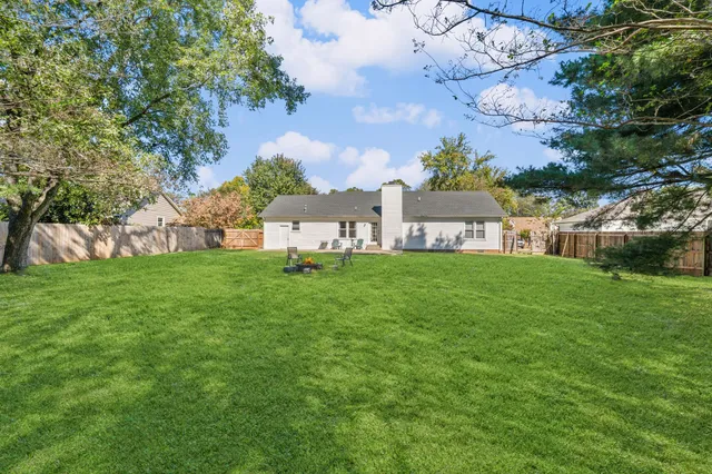 a front view of house with yard and trees in the background