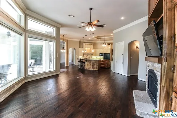 a view of a livingroom with furniture a fireplace wooden floor and a large window