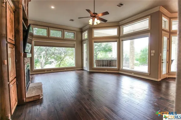 an empty room with wooden floor and windows