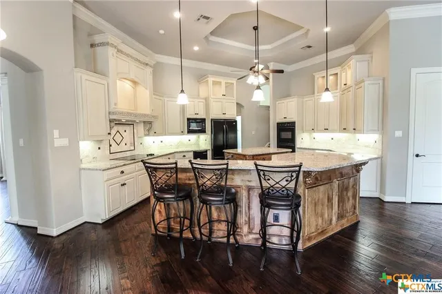 a kitchen with stainless steel appliances a dining table chairs stove and cabinets