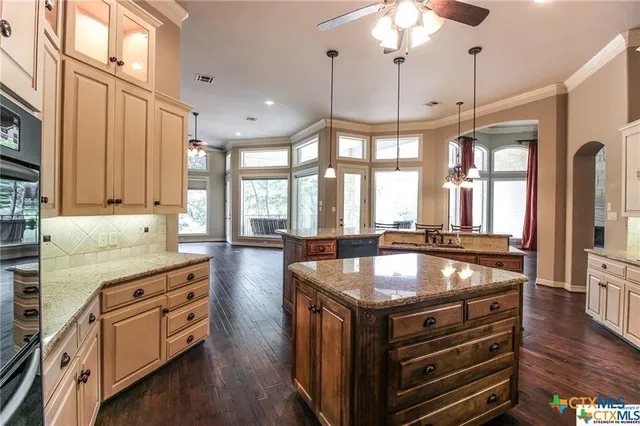 a large kitchen with granite countertop lots of counter space dining table and stainless steel appliances