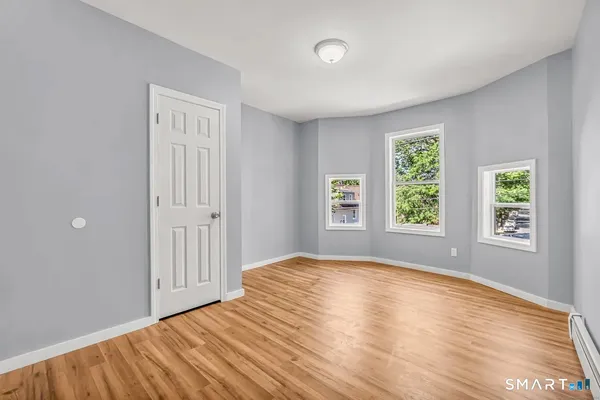 a view of an empty room with wooden floor and a window