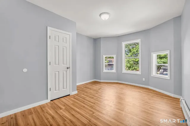 a view of an empty room with wooden floor and a window