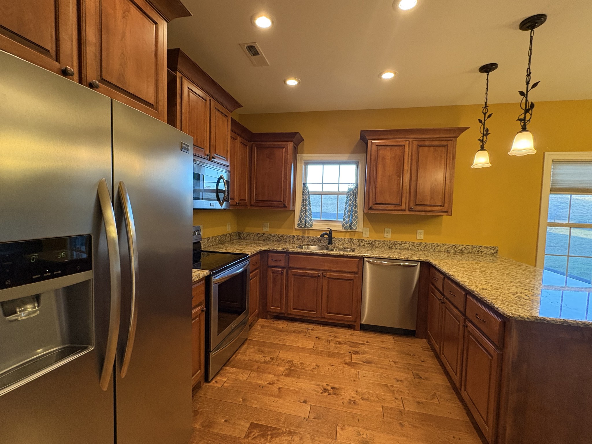 117 Grayson Lane White House, TN 37188 - Photo 7 of 24 a kitchen with stainless steel appliances granite countertop a refrigerator a sink dishwasher a stove and a dining table with wooden cabinet