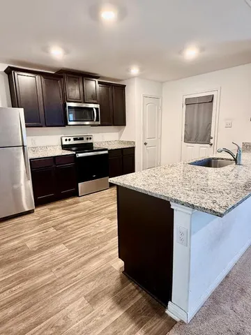 a kitchen with kitchen island stainless steel appliances a sink and a refrigerator