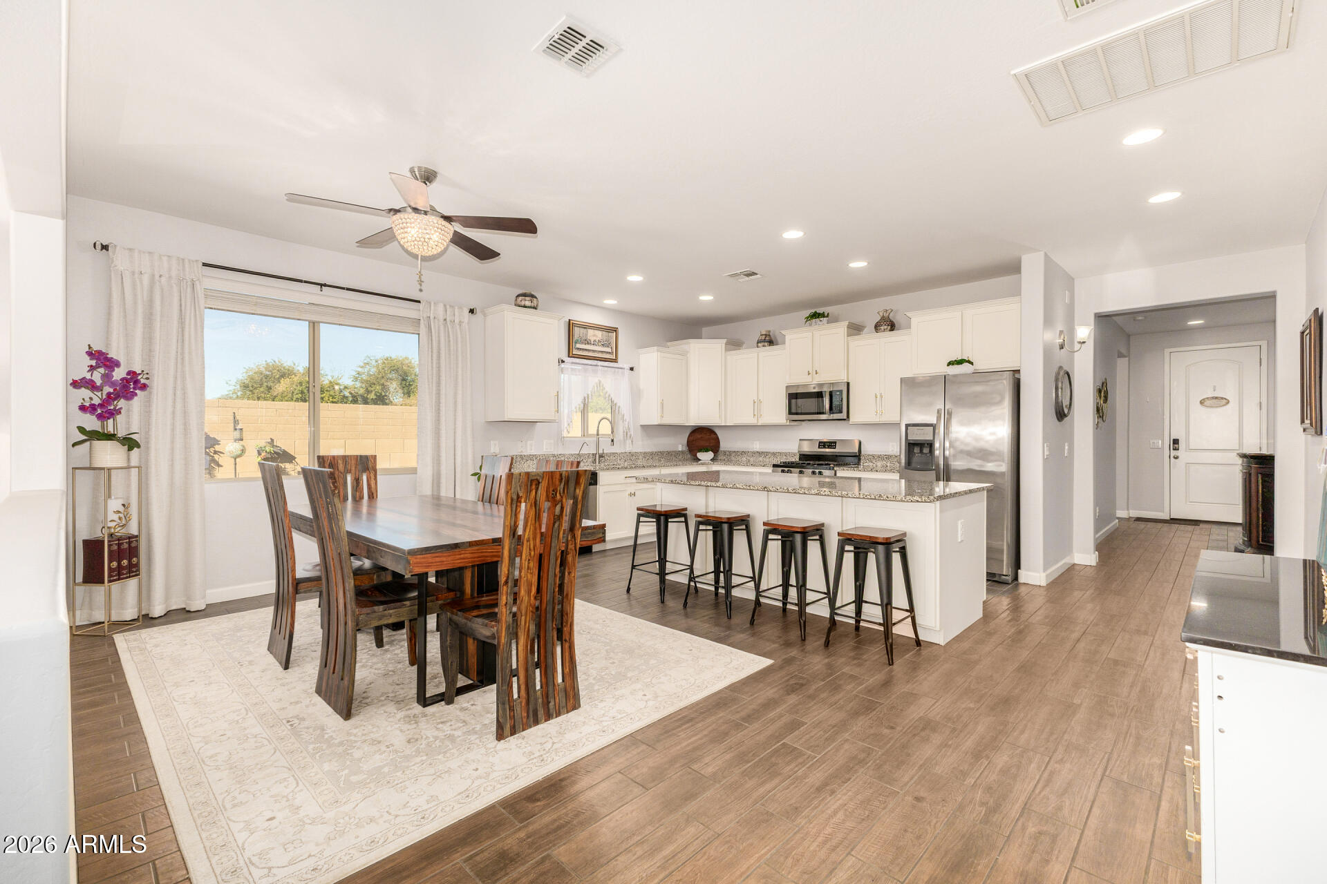 41039 West Williams Way Maricopa, AZ 85138 - Photo 4 of 25 a view of a dining room and livingroom with furniture wooden floor a rug a fireplace