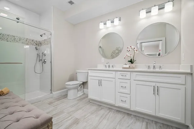 a bathroom with a double vanity sink toilet and a mirror