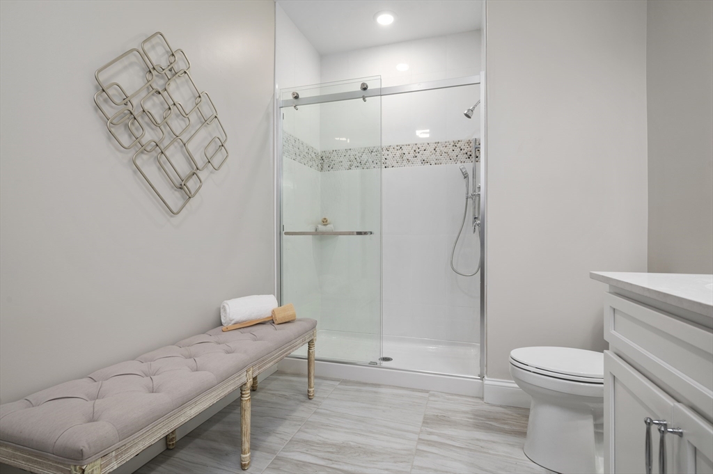 36 Old Louisquisset Pike, Unit 106 North Smithfield, RI 02896 - Photo 20 of 30 a bathroom with a granite countertop sink a toilet and shower